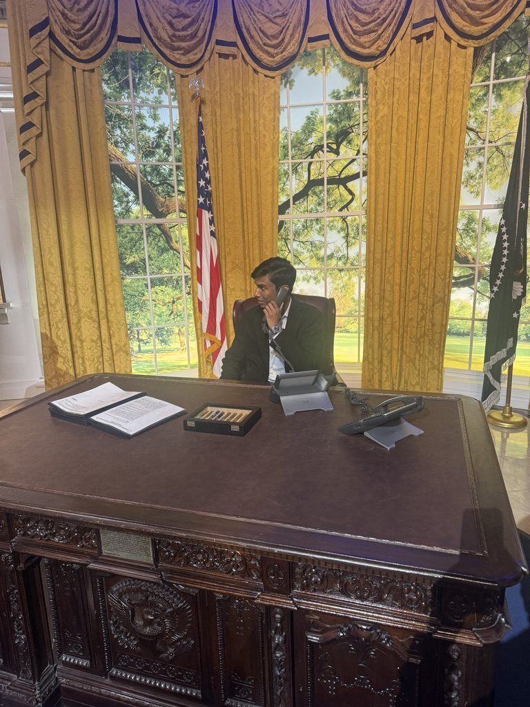 Priyam on the phone at the Resolute desk in an Oval Office replica